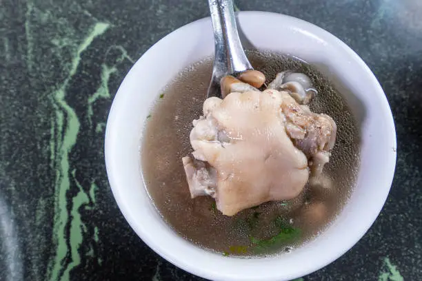 Photo of Taiwan's distinctive famous snacks: Peanut pork knuckle(pig's trotter) soup in a white bowl on stone table, Taiwan Delicacies, Taiwan Street Food