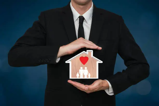 Business man covering an home family house with love. Safety and security concept