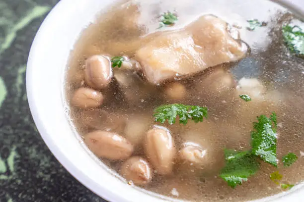 Photo of Taiwan's distinctive famous snacks: Peanut pork knuckle(pig's trotter) soup in a white bowl on stone table, Taiwan Delicacies, Taiwan Street Food