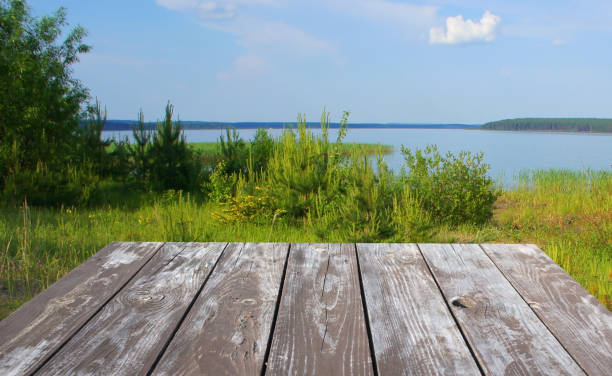 istock Empty wooden Board table on nature background. Landscape with pond and forest. 985807452