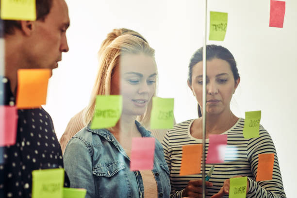 istock Group of smiling office colleagues brainstorming with sticky notes 985808674