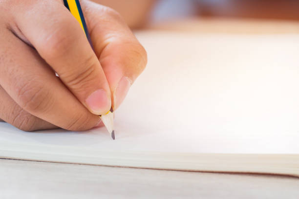 istock Education test concept : Man Hands high school, university student holding pencil for testing exams writing answer sheet and exercise for taking in exam paper on wood table at classroom 985811590