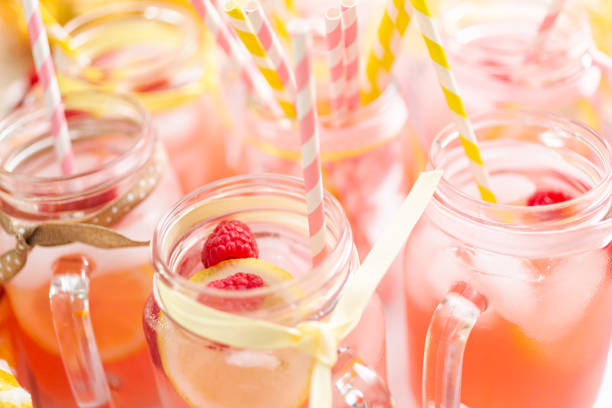 istock Raspberry lemonade garnished with fresh lemon and raspberries in drinking mason jars. 985820844