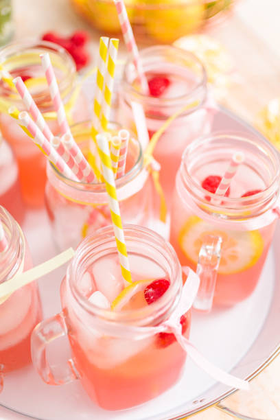 istock Raspberry lemonade garnished with fresh lemon and raspberries in drinking mason jars. 985820884