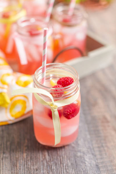 istock Raspberry lemonade garnished with fresh lemon and raspberries in drinking mason jars. 985821038