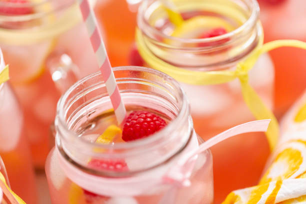 istock Raspberry lemonade garnished with fresh lemon and raspberries in drinking mason jars. 985821040