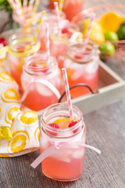 istock Raspberry lemonade garnished with fresh lemon and raspberries in drinking mason jars. 985821122