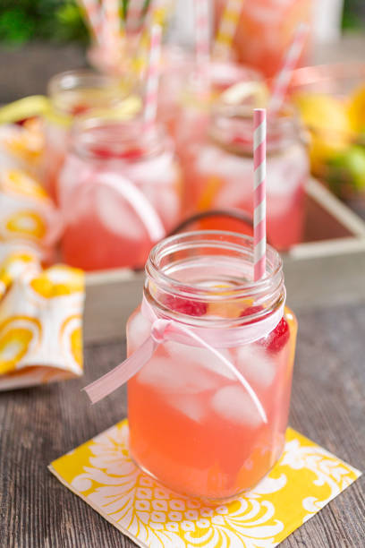 istock Raspberry lemonade garnished with fresh lemon and raspberries in drinking mason jars. 985821132