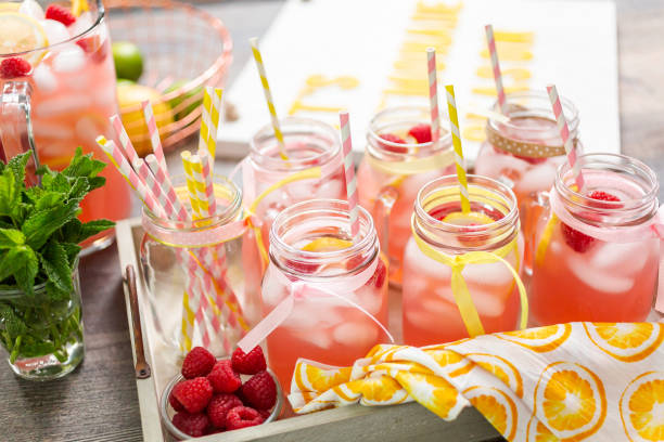 Raspberry lemonade garnished with fresh lemon and raspberries in drinking mason jars. Raspberry lemonade garnished with fresh lemon and raspberries in drinking mason jars. mason jar lemonade stock pictures, royalty-free photos & images