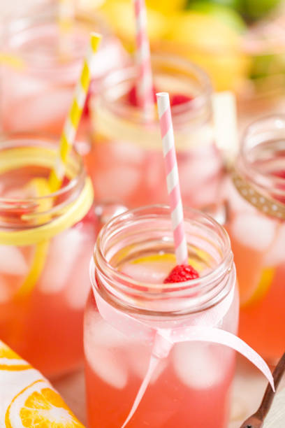 istock Raspberry lemonade garnished with fresh lemon and raspberries in drinking mason jars. 985821246