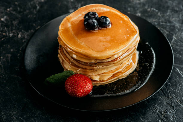 istock stack of freshly backed pancakes with berries on black table 985843954