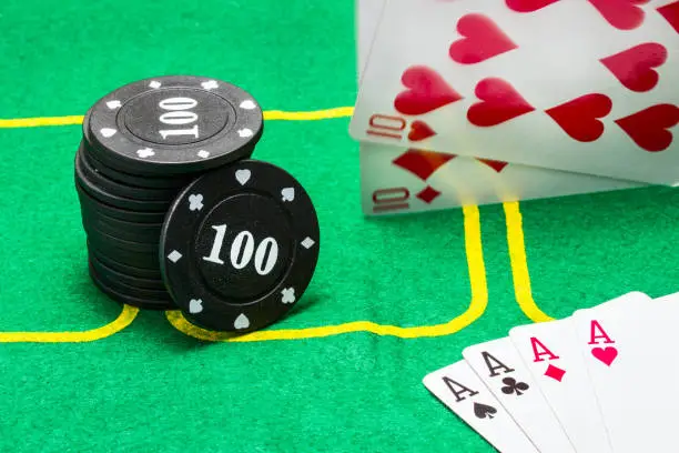 Photo of column of black chips for poker falling cards and a combination of four aces