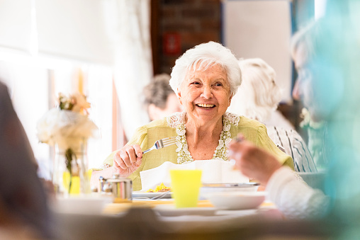 Retrato de una sonriente mujer senior almorzar con amigos photo