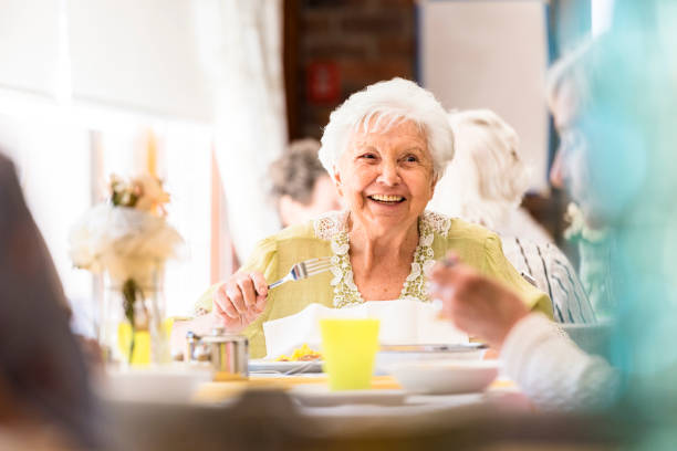 友人と昼食を食べて笑顔の年配の女性の肖像画 - リ��タイアメントコミュニティ ストックフォトと画像