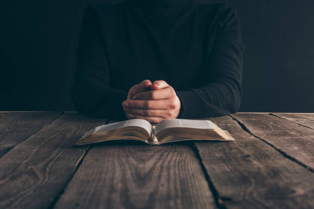 istock cropped image of nun sitting at table with bible and praying 985865716