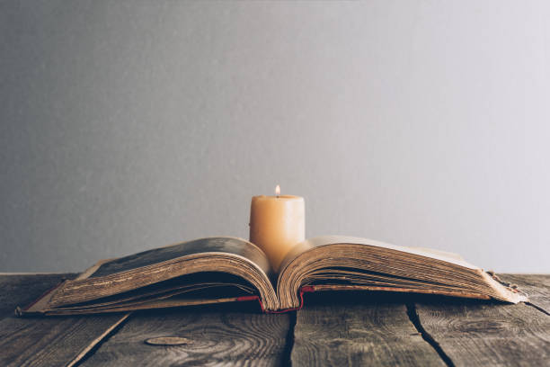 istock open holy bible with candle on wooden table 985870118
