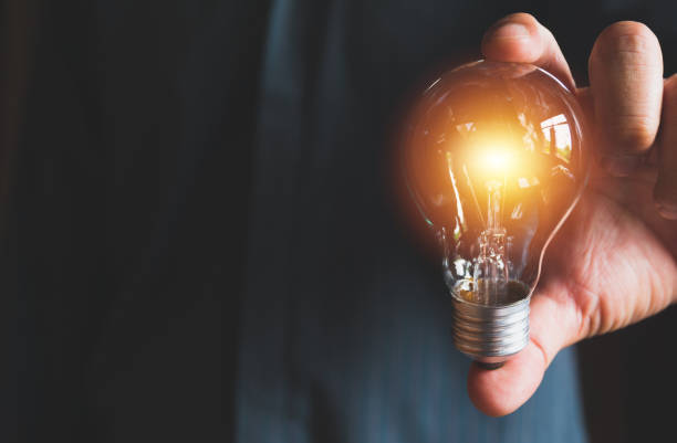 istock Hand of male holding a light bulb for innovation and creative concept . 985870192