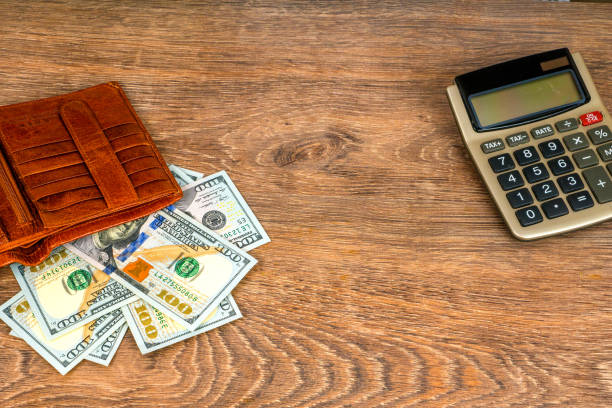 istock opened wallet with dollar banknotes and calculator on table, top view 985883762