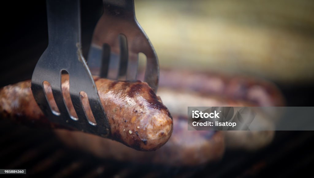 Taking Sausage off the grill Barbecue - Meal Stock Photo