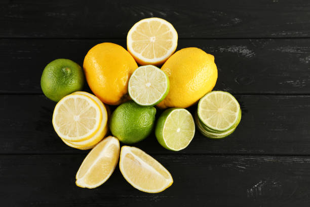 istock Ripe limes and lemons on black wooden table 985896402