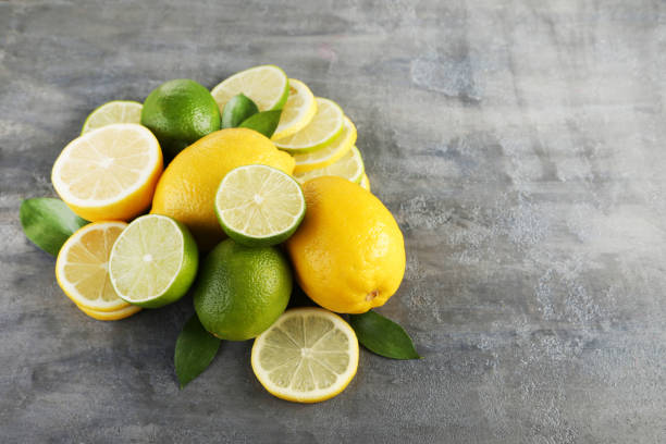 istock Ripe limes and lemons with leafs on grey wooden table 985898548