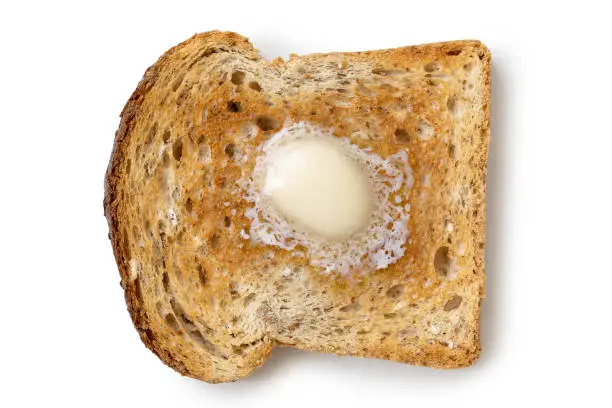 A single slice of whole wheat toast with a knob of melting butter isolated on white from above.