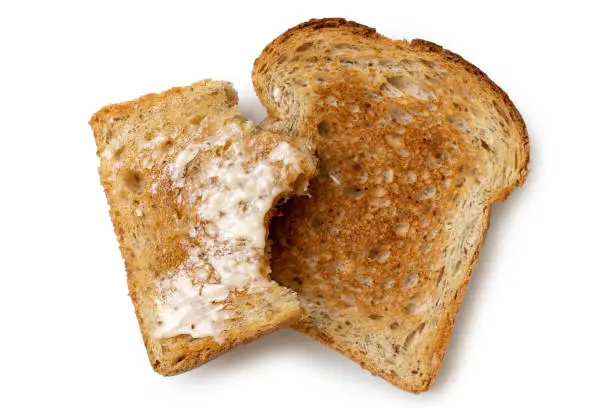 Half eaten buttered slice of whole wheat toast and whole dry slice of toast isolated on white from above.