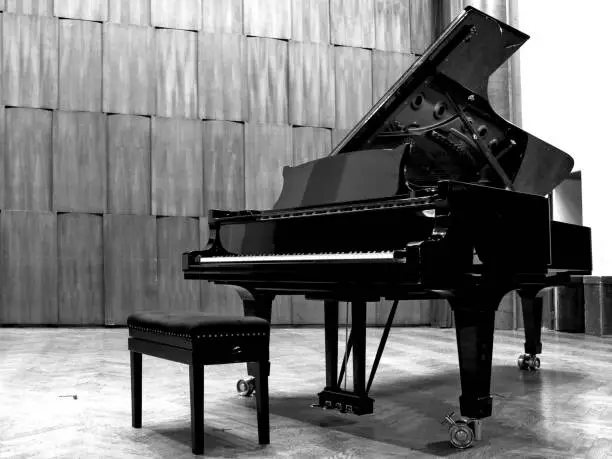 Photo of Black grand piano on stage, b&w