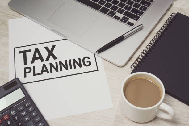 istock Tax Planning on white paper with laptop computer and coffee cup. 985903182