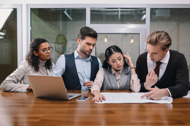 istock concentrated multicultural businesspeople working with digital devices and documents in office 985908178