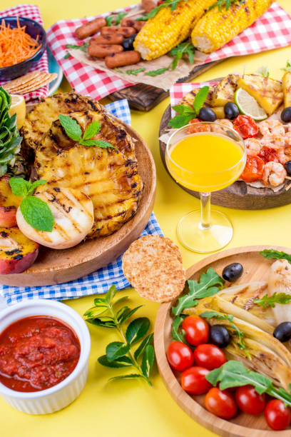 istock Different fruits and vegetables on grilled and shrimp. Yellow background. Summer dinner. Copy space 985908986