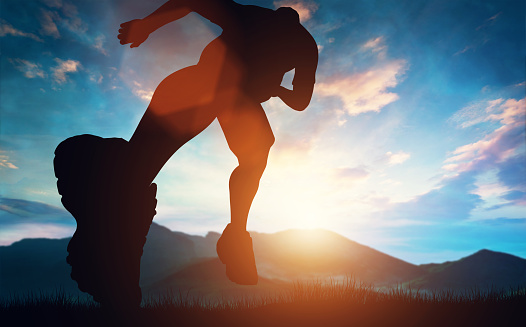 Hombre corriendo hacia la puesta de sol en las montañas photo