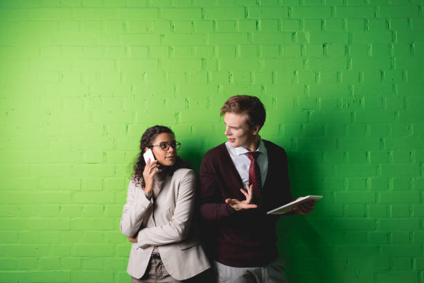 istock multiethnic businesspeople using digital tablet and smartphone in front of green wall 985914592