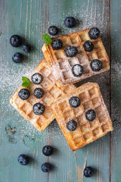 istock Waffles with blueberries on a rustic green and blue background. View from above. 985914776