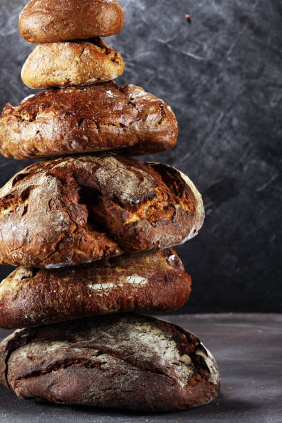 istock Different kinds of bread and bread rolls on board from above. Kitchen or bakery 985925636