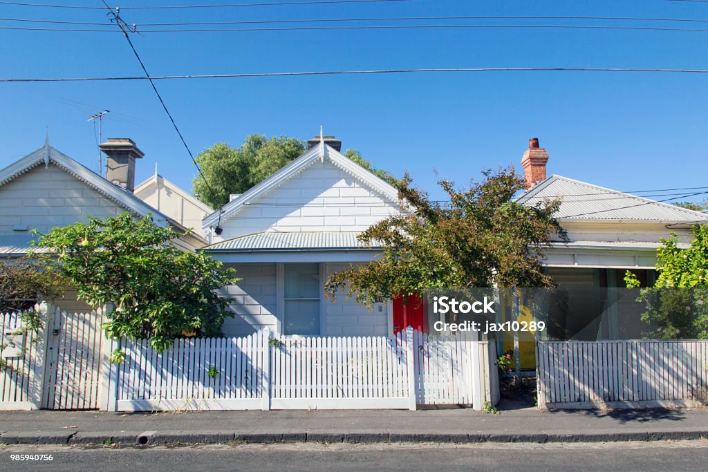 Charming bungalow homes with white picket fence. Row of detached bungalow homes in the residential suburb of St Kilda in Melbourne with white picket fence and a blue sky background. Power cables overhead. Australia Stock Photo