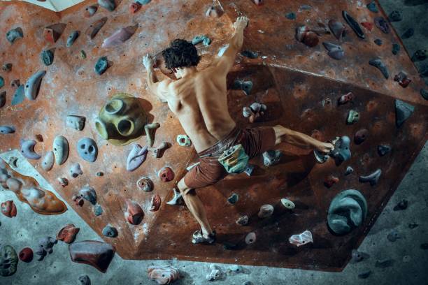 libero scalatore giovane arrampicata masso artificiale al chiuso - hanging on rock rock climbing foto e immagini stock