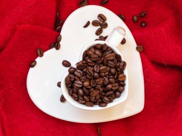 istock Heart shaped cup with coffee beans on red 985954944