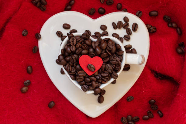 istock Heart shaped cup with coffee beans on red 985959914
