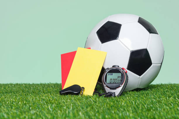 Football or Soccer Referee equipmnt and ball on grass with green background.