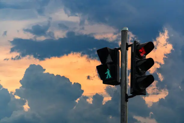 Traffic light: green light for people walking across the street. With red light, do not turn right. On the background of the dark sky in the sunset time. Copy space.