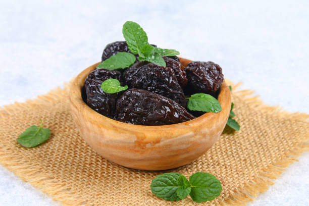 istock Prunes and fresh mint leaves in a bowl on a concrete table. 985984494