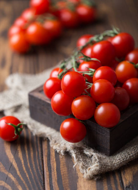 istock Small red cherry tomatoes on rustic background. Cherry tomatoes on the vine 985984618