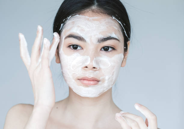istock Young beautiful woman washing her face with hands by soap. Studio shot 986020986
