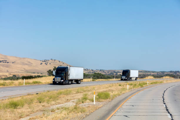 istock Two semi trucks carry trailers on interstate highway, California, USA 986031938