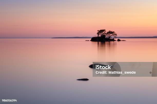Beautiful Colors With Stones In The Lake And A Small Island In The Back Stock Photo - Download Image Now