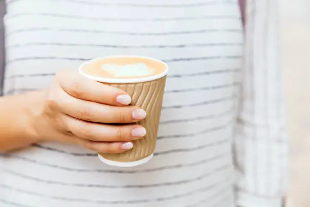 Cup of cappuccino in female hand with fashion manicure.