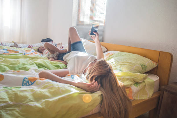 istock Mother and daughter using mobile phone in bed 986068446