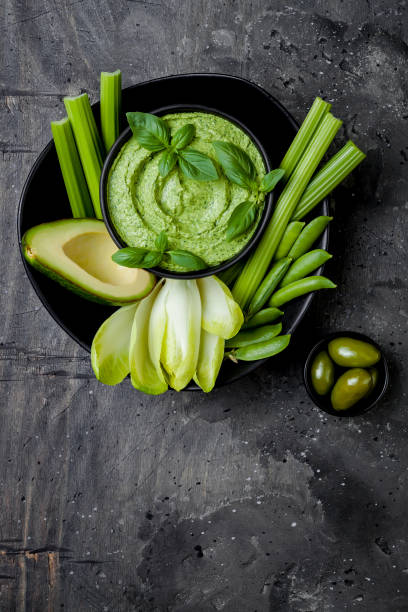istock Green vegetables snack board with herb hummus or pesto dip. Healthy raw summer appetizer platter. Copy space 986069178