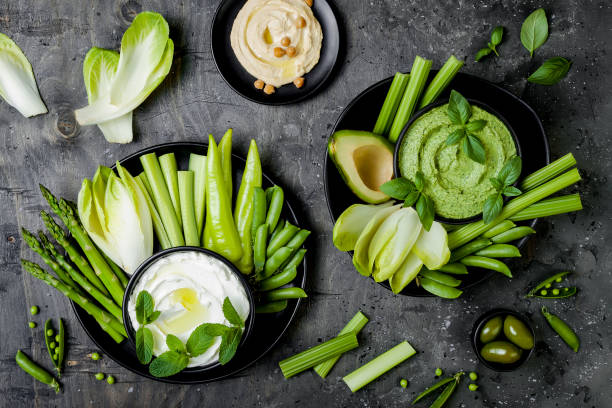 istock Green vegetables snack board with various dips. Yogurt sauce or labneh, hummus, herb hummus or pesto with fresh vegetables. Healthy raw summer platter. 986069210
